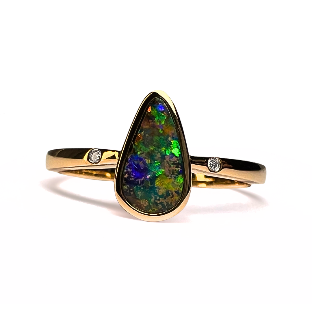 Gold ring with a teardrop-shaped opal stone on a white background