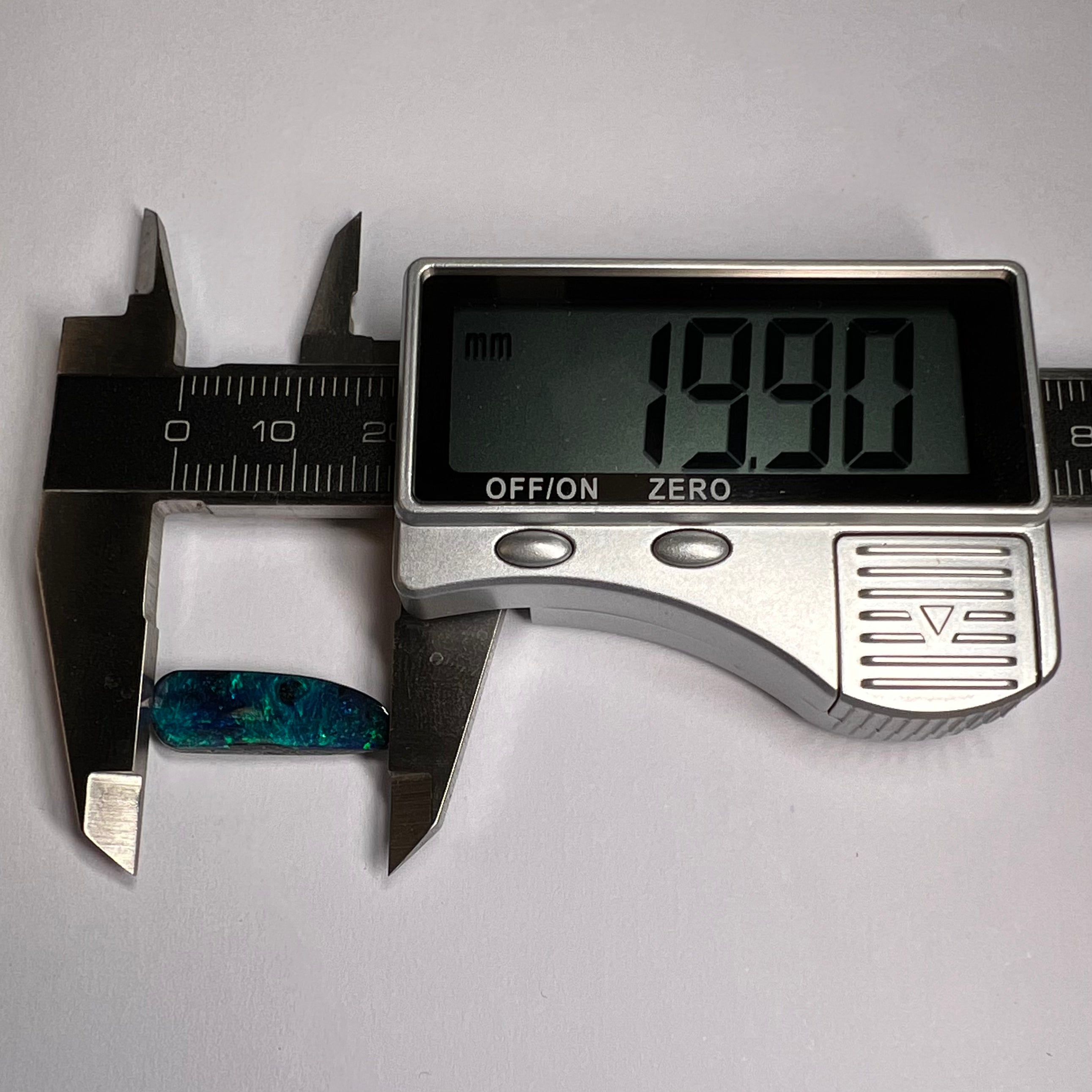 Digital caliper measuring a piece of jewelry on a white background