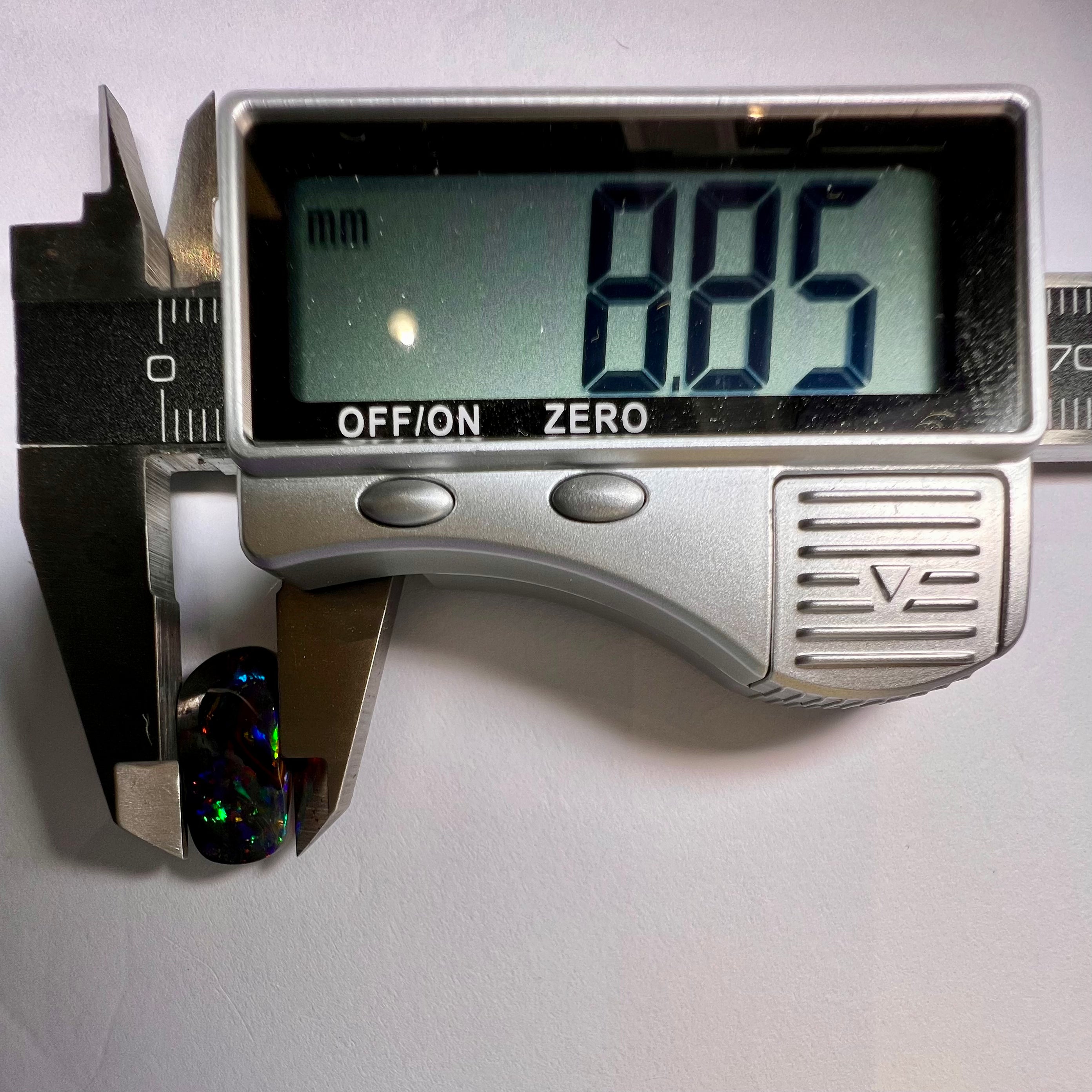 Digital caliper measuring a stone with a displayed measurement of 8.85 mm on a white background.