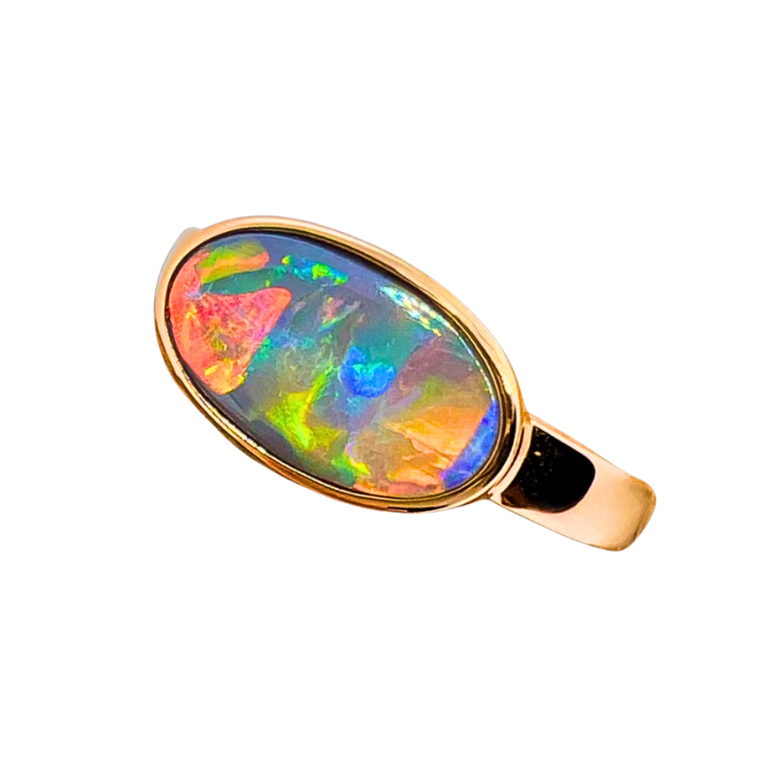 Red green and blue opal gemstone on a rose gold ring with a white background.