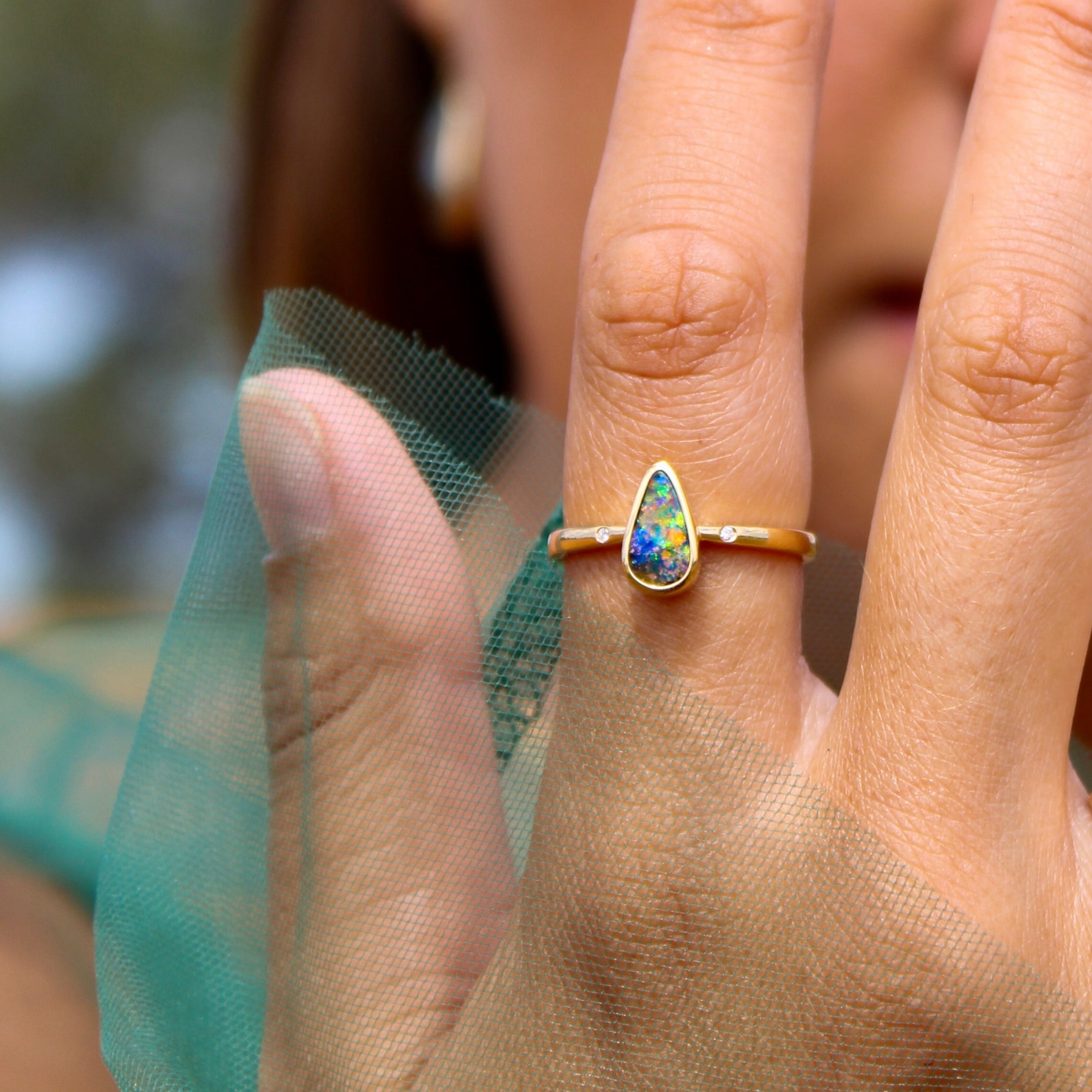 Close-up of a hand wearing an opal rings with a blurred background