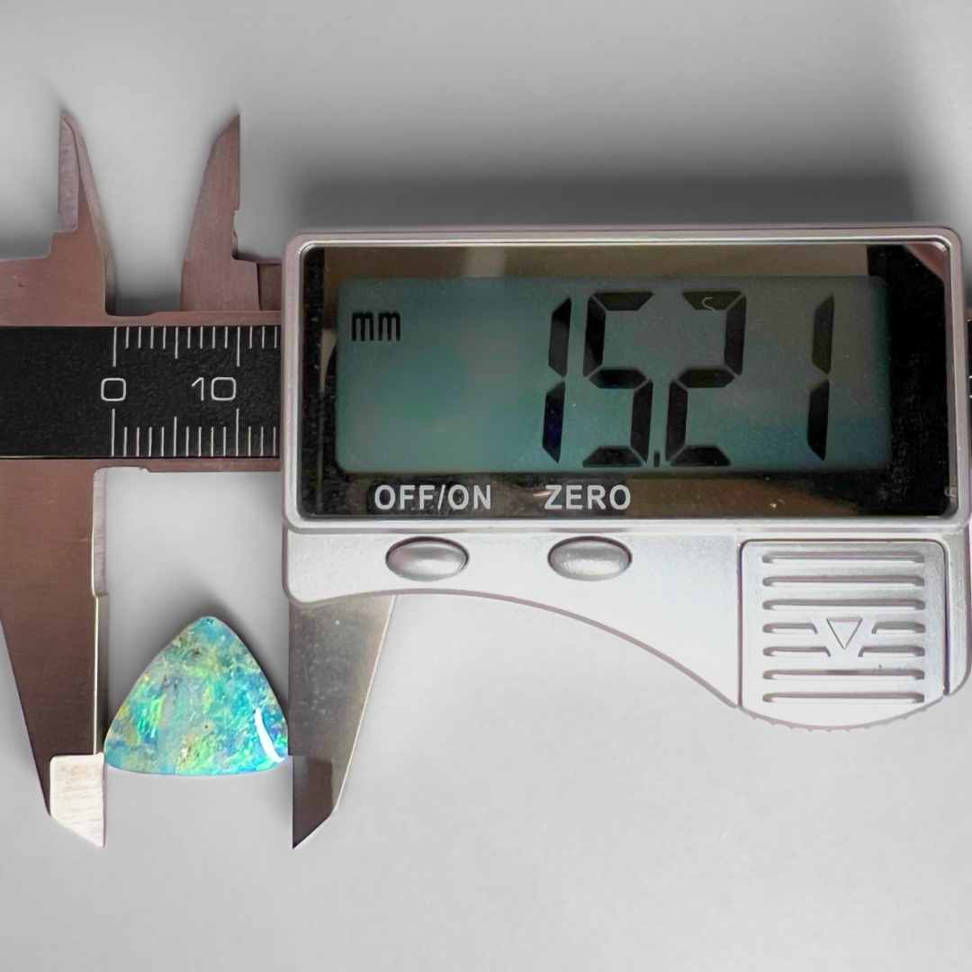Digital caliper measuring a colorful gemstone with a clear background