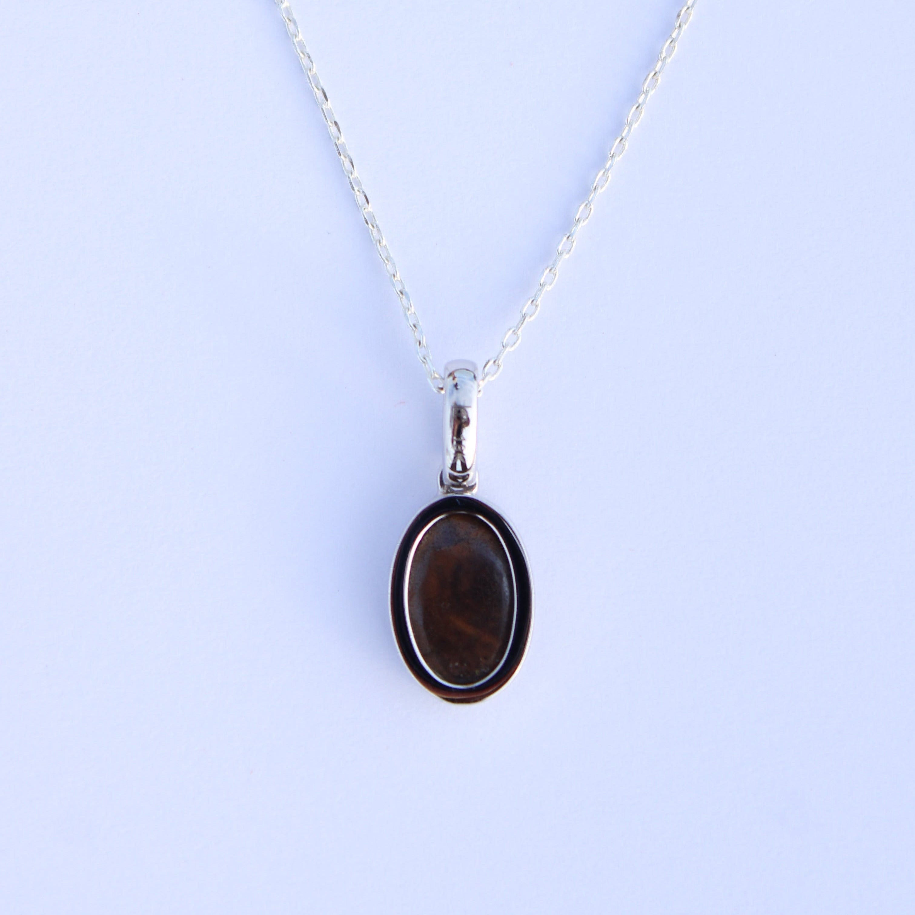 Necklace with a pendant featuring a brown stone on a light blue background